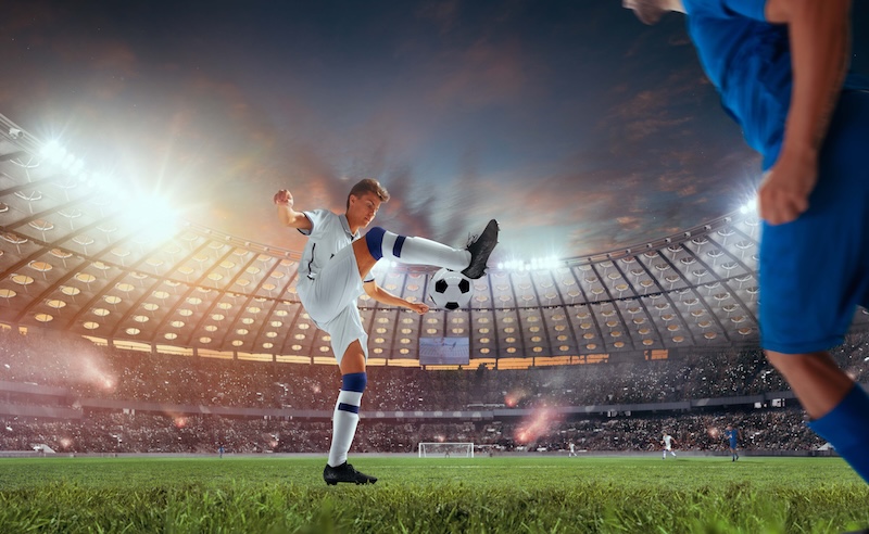 En fotbollsspelare som dribblar på arena